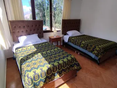 a bedroom with two beds and a window at Casa de Campo Apu San Isidro in Urubamba
