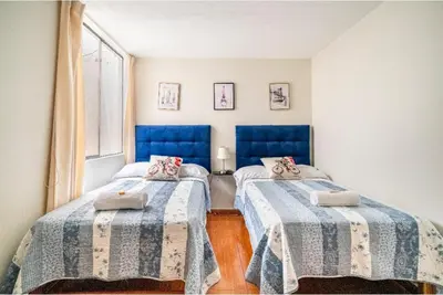 a bedroom with two beds with blue headboards and a window at Lopez House Family Aparment in Lima