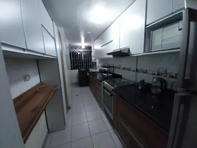 a kitchen with white cabinets and a black counter top at Amplio Departamento amoblado, Condominio Parques de la Huaca - San Miguel in Lima