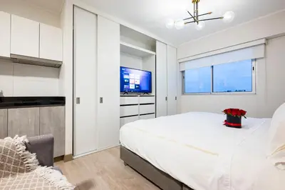 a white bedroom with a large bed and a tv at Connect Studios by Vibrant in Lima