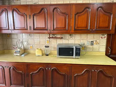 a kitchen with wooden cabinets and a microwave on a counter at Casa de Campo Condominio El Pueblo-Santa Clara,Ate in Lima
