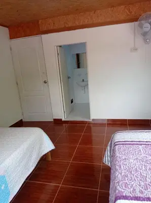 a room with two beds and a bathroom with a shower at Hospedaje Casablanca in Pozuzo
