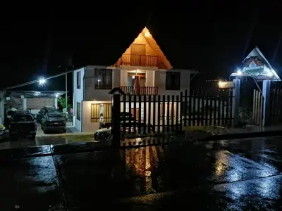 a house on a rainy night with a fence at Hospedaje Casablanca in Pozuzo