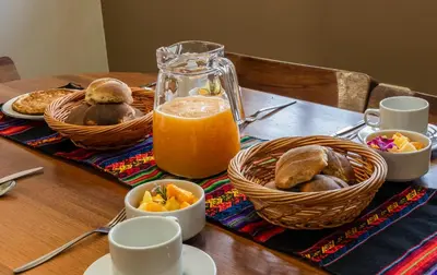 a table with bread and a jug of orange juice at La Rosa Wellness Lodge in Urubamba