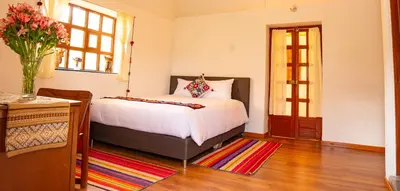 a bedroom with a bed and a vase of flowers at La Rosa Wellness Lodge in Urubamba