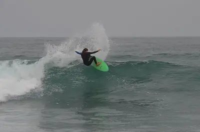 a person riding a wave on a surfboard in the ocean at Condominio Ocean reef in San Bartolo