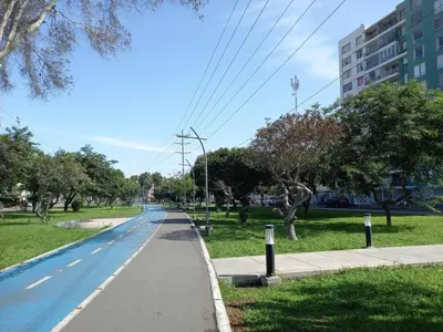 an empty street in a park with trees and a building at San Miguel Rooms Lima Airport B&B in Lima