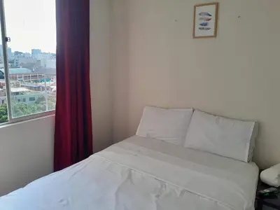 a white bed in a room with a window at San Miguel Rooms Lima Airport B&B in Lima
