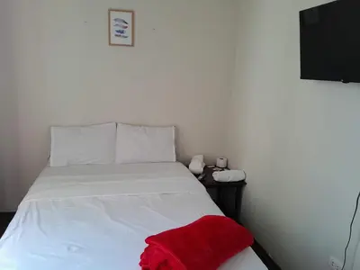 a bedroom with a white bed with a red blanket on it at San Miguel Rooms Lima Airport B&B in Lima