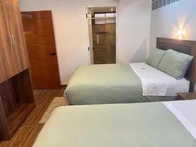 a hotel room with two beds and a door at Lama Vista Living 201 in Cusco