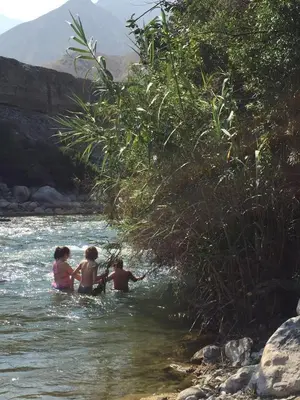 three people sitting in the water in a river at Soy y Luna- ECOALBERGUE RETABLOS PERU in Lunahuaná