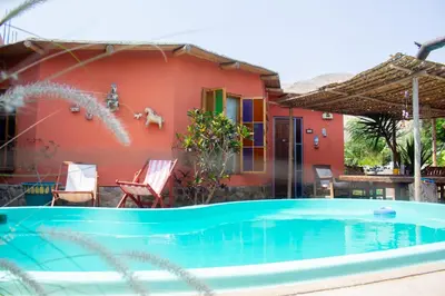 a villa with a swimming pool in front of a house at Soy y Luna- ECOALBERGUE RETABLOS PERU in Lunahuaná