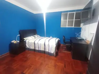 a bedroom with blue walls and a bed and a desk at Eli Travelers House in Lima