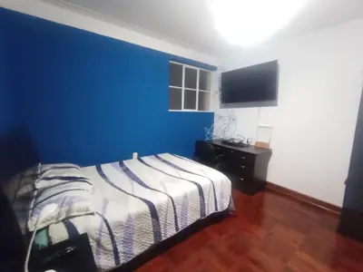 a bedroom with a blue wall and a bed at Eli Travelers House in Lima