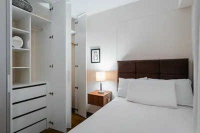a white bedroom with a bed and a night stand with a lamp at Family-Friendly 2BR in Prime Location in Lima