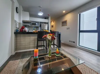 a living room with a vase of flowers on a glass table at Apartamento completo en Barranco in Lima