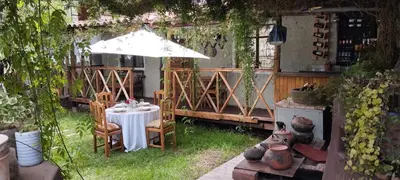 a table and chairs in a garden with an umbrella at Casa Jazmín Hospedaje Familiar Eco Amigable - Huayoccari, Sacred Valley in Huayoccare
