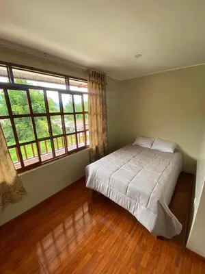 a bedroom with a bed and two large windows at LagunaNegra Oxapampa in Palmira