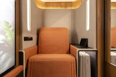 an orange chair and a laptop on a train at Sleepover - Lima Airport, the only in-terminal sleep pods in Lima
