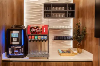 a drink station with a cocacola machine on a counter at Sleepover - Lima Airport, the only in-terminal sleep pods in Lima