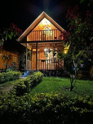 a small wooden house with a lit up facade at Palo Alto Lodge in Oxapampa