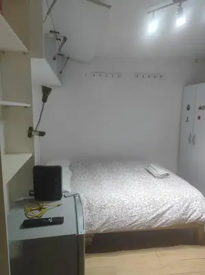 a white room with a bed and a desk with a laptop at Cómodo Estudio Miraflores in Lima