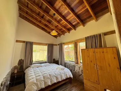 a bedroom with a large bed in a room with windows at casa de campo con jaccuzi in Huaran