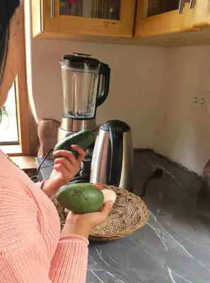 a woman is holding two cucumbers in front of a blender at casa de campo con jaccuzi in Huaran