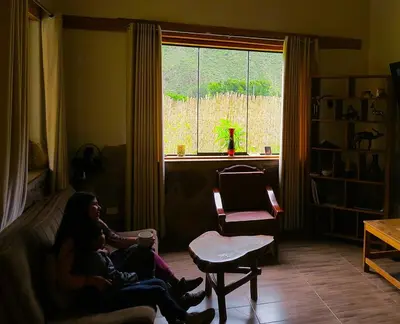 a woman sitting on a couch in a living room at casa de campo con jaccuzi in Huaran