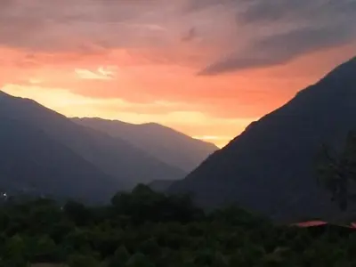 a sunset in the mountains with trees in the foreground at HOTEL HUAYTARA CasaBlanca in Huaytará