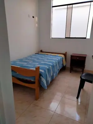 a bedroom with a bed with a blue comforter and a window at Departamento Pisco - San Andrés, cerca a Paracas in Gallinazos Hacienda