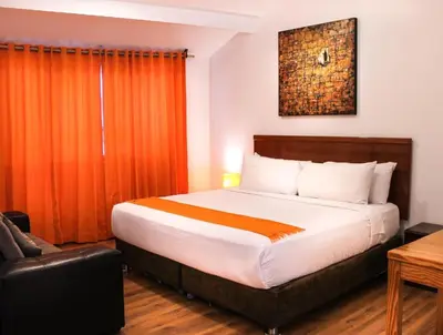 a bedroom with a large bed with an orange curtain at Suites Machupicchu in Machu Picchu