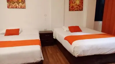 two beds with orange and white sheets in a room at Suites Machupicchu in Machu Picchu