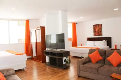 a hotel room with a bed and a couch and a tv at Suites Machupicchu in Machu Picchu