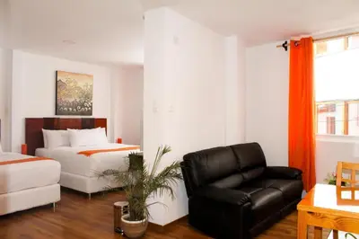 a bedroom with a bed and a black leather chair at Suites Machupicchu in Machu Picchu
