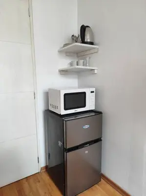 a microwave on top of a refrigerator in a kitchen at Cómoda habitación independiente in Lima