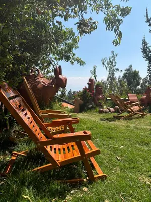 a group of wooden chairs sitting in the grass at Antawara Glamping in Chipingura