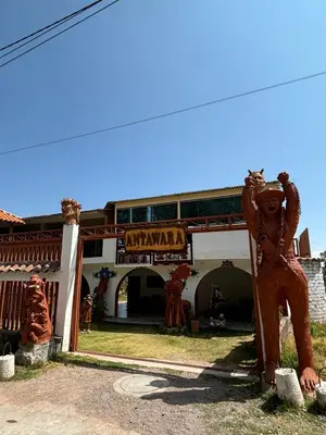 a building with two wooden statues in front of it at Antawara Glamping in Chipingura