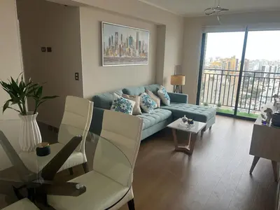 a living room with a blue couch and a glass table at Deluxe Aparment San Isidro in Lima
