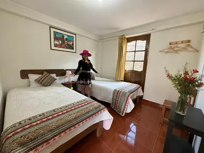 a little girl standing between two beds in a room at Tambo Real Valle Sagrado in Yucay