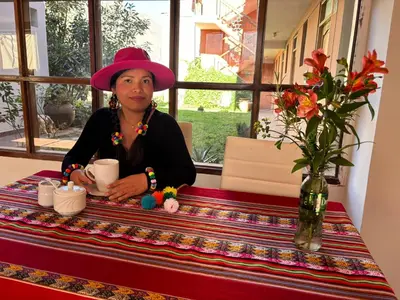 a woman sitting at a table with a cup of coffee at Tambo Real Valle Sagrado in Yucay
