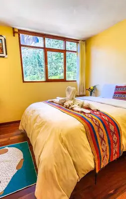 a bedroom with two beds and a window at PERU QUECHUA'S LODGE Riverside in Ollantaytambo