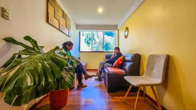 two people sitting on a couch in a living room at PERU QUECHUA'S LODGE Riverside in Ollantaytambo