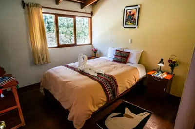 a bedroom with a bed with a stuffed animal on it at PERU QUECHUA'S LODGE Riverside in Ollantaytambo