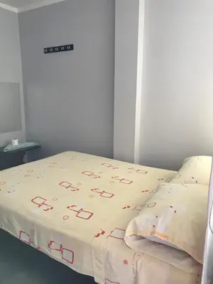 a bed with a white comforter with red letters on it at Hospedaje D Francisco in Lima