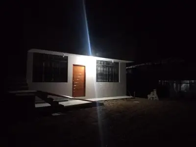 a small white house with a door at night at Yompor's haus in Oxapampa