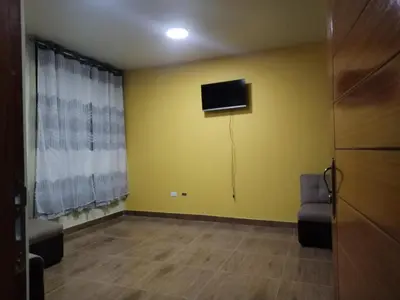 a living room with a tv on a yellow wall at Yompor's haus in Oxapampa