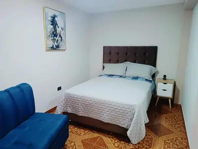 a bedroom with a bed and a blue couch at departamento airport in Lima