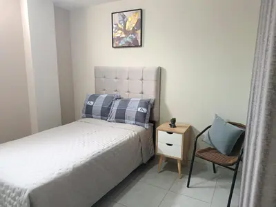 a small bedroom with a bed and a chair at departamento airport in Lima