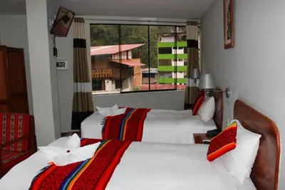 a hotel room with two beds and a window at Hotel Wiracocha Machupicchu in Machu Picchu